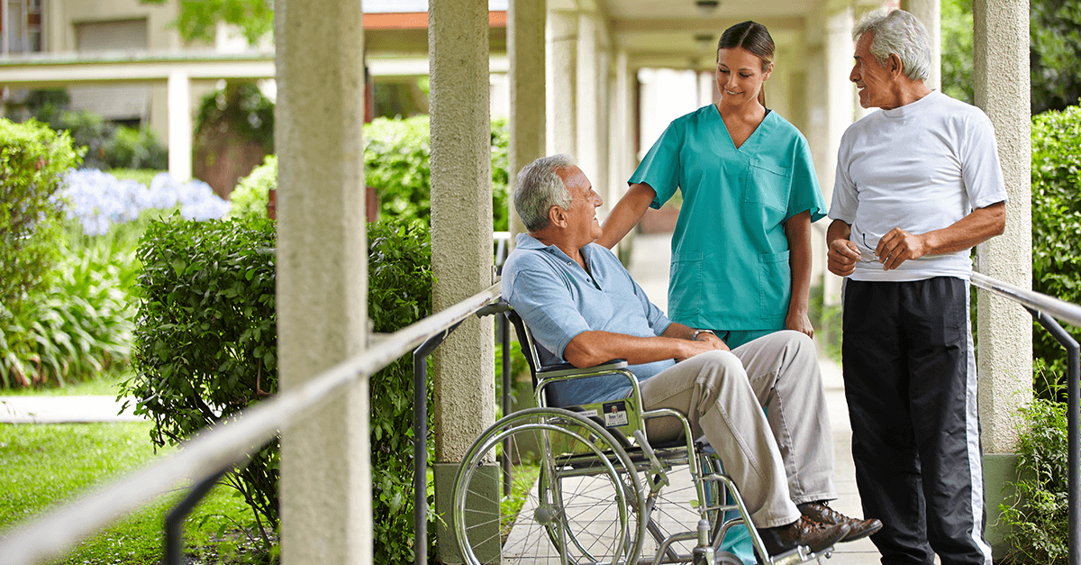 outdoor scene image with two elderly men and a caretaker.